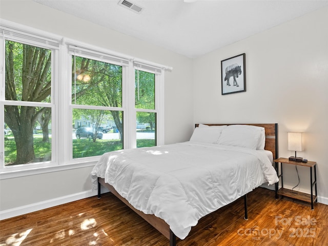 bedroom with visible vents, baseboards, and wood finished floors