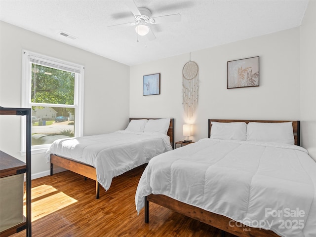 bedroom featuring ceiling fan, wood finished floors, and visible vents