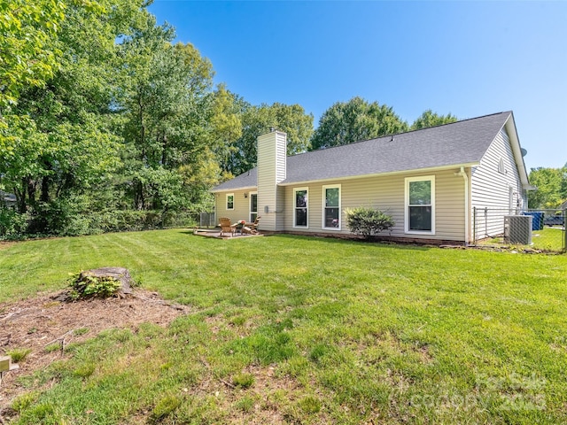 back of property with fence, roof with shingles, a chimney, cooling unit, and a yard