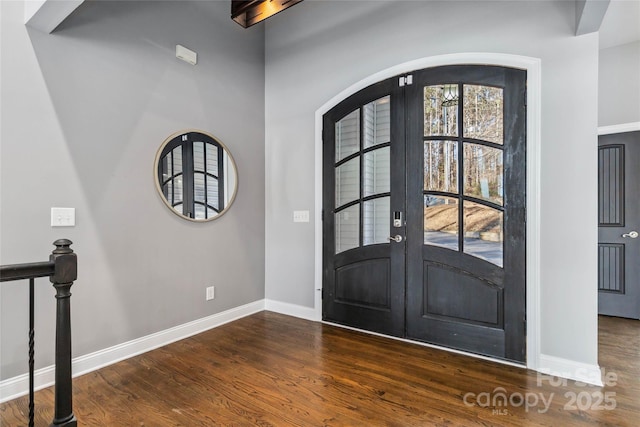 foyer entrance with baseboards, french doors, arched walkways, and wood finished floors