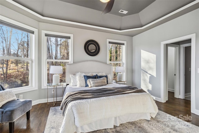 bedroom featuring visible vents, a raised ceiling, baseboards, and wood finished floors