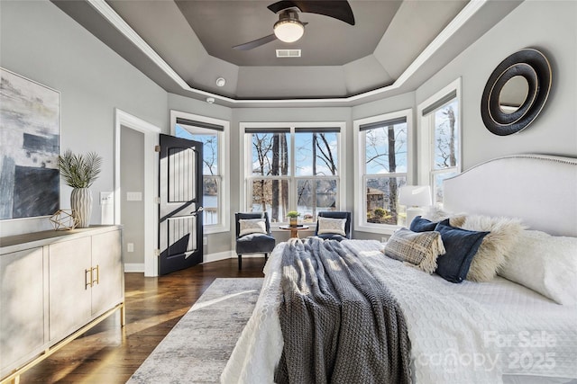 bedroom featuring baseboards, a raised ceiling, dark wood-style flooring, and multiple windows