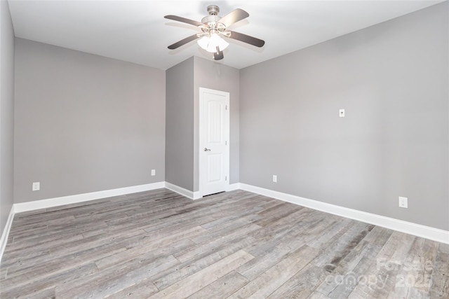 spare room featuring baseboards, ceiling fan, and wood finished floors