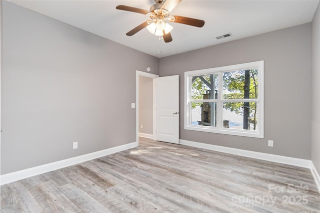 spare room with baseboards, a ceiling fan, wood finished floors, and visible vents