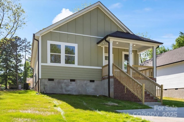 bungalow-style house featuring board and batten siding, crawl space, central AC unit, stairway, and a front lawn