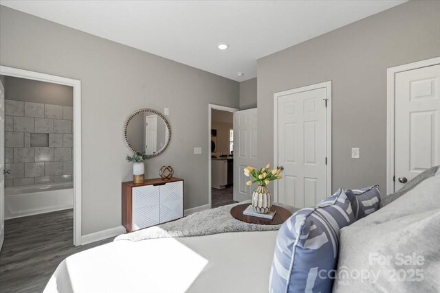 bedroom with baseboards, ensuite bath, and wood finished floors