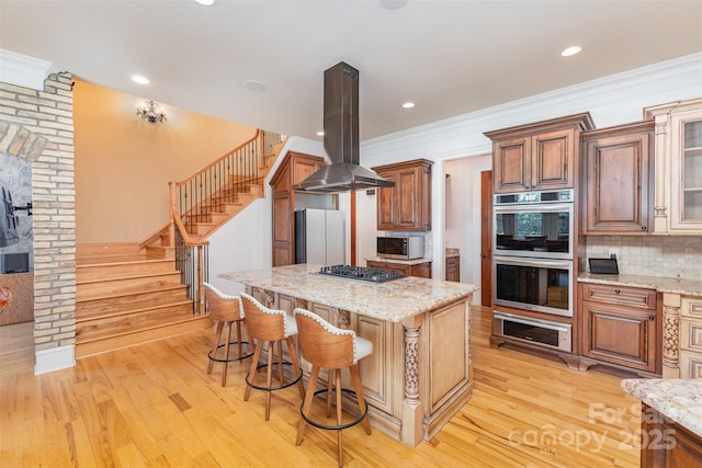 277 Tradition Dr, Mount Gilead, NC 27306 - kitchen with a kitchen bar, island range hood, a center island, light wood-style floors, and stainless steel appliances