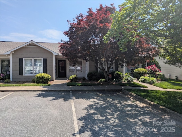 view of front of home featuring uncovered parking and roof with shingles
