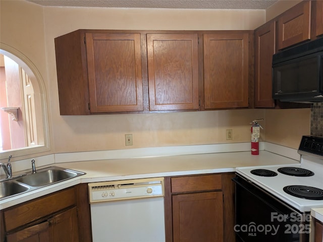 kitchen featuring light countertops, a sink, range with electric cooktop, dishwasher, and black microwave