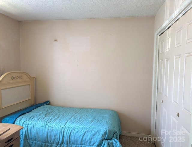carpeted bedroom with a textured ceiling and baseboards
