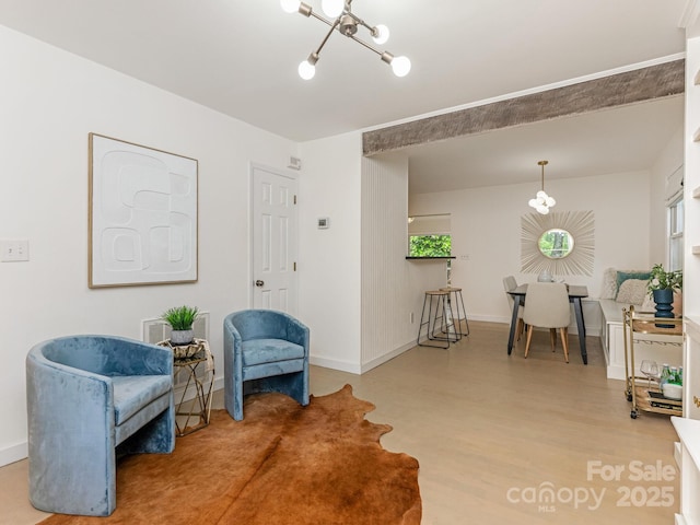 living area featuring a chandelier, wood finished floors, and baseboards