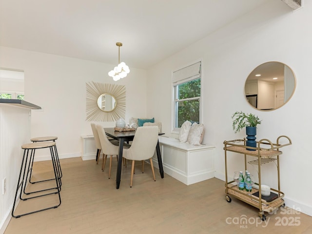 dining space featuring light wood-style flooring, baseboards, and a chandelier