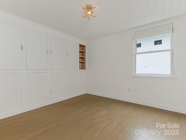 spare room featuring wood finished floors, wooden ceiling, baseboards, and built in shelves