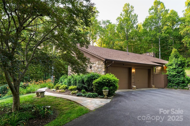 461 Sugar Hollow Rd, Fairview, NC 28730 - view of side of property with a garage, asphalt driveway, stone siding, a shingled roof, and a chimney