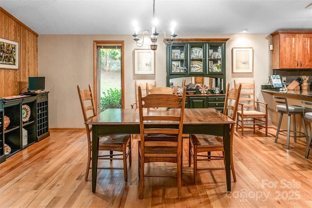461 Sugar Hollow Rd, Fairview, NC 28730 - dining room featuring light wood finished floors, wooden walls, a chandelier, and a textured ceiling