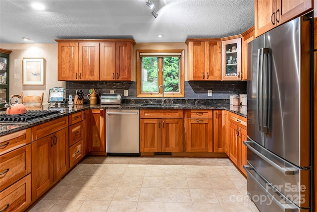 461 Sugar Hollow Rd, Fairview, NC 28730 - kitchen with stainless steel appliances, a textured ceiling, brown cabinetry, backsplash, and dark stone counters