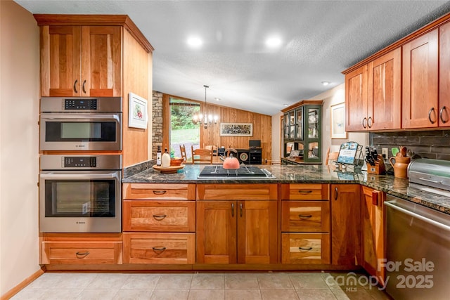 461 Sugar Hollow Rd, Fairview, NC 28730 - kitchen with appliances with stainless steel finishes, a chandelier, brown cabinets, a peninsula, and vaulted ceiling
