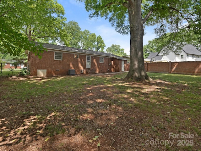 rear view of house featuring a yard, brick siding, crawl space, and fence