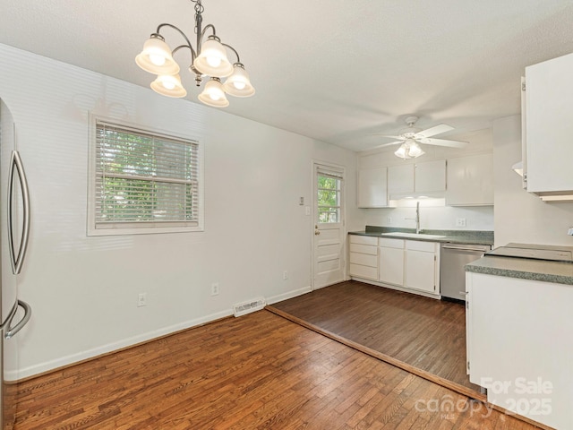 kitchen featuring ceiling fan with notable chandelier, a sink, stainless steel appliances, white cabinetry, and dark wood finished floors