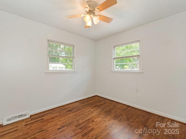 spare room with a ceiling fan, visible vents, wood finished floors, and baseboards