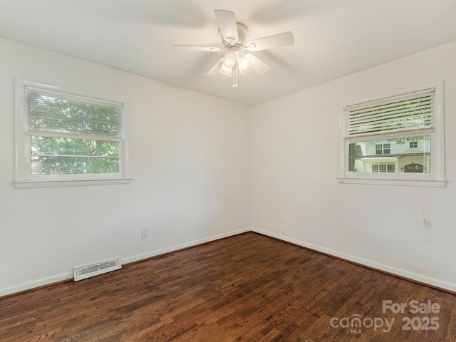 spare room featuring dark wood finished floors, visible vents, baseboards, and a ceiling fan