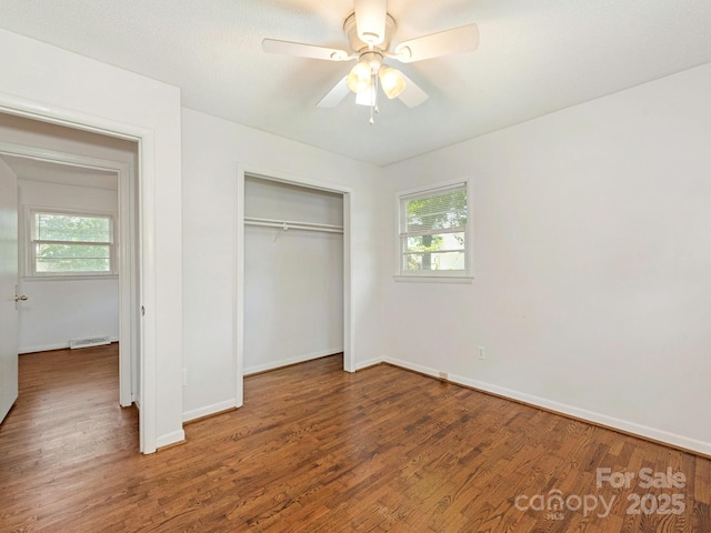 unfurnished bedroom featuring wood finished floors, a closet, visible vents, and multiple windows