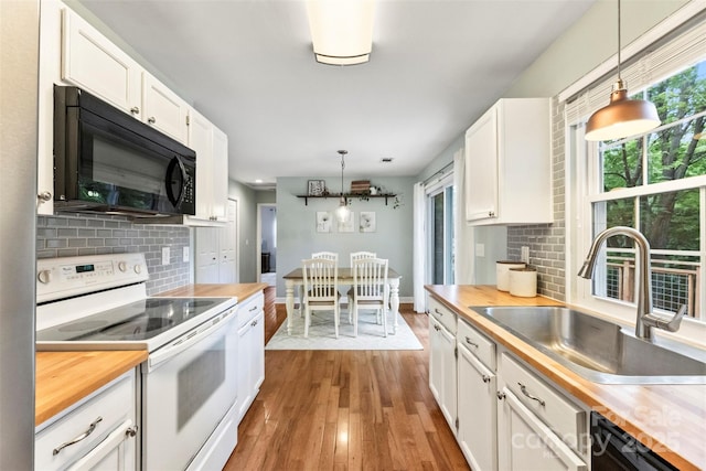 kitchen featuring electric stove, black microwave, butcher block counters, a sink, and wood finished floors