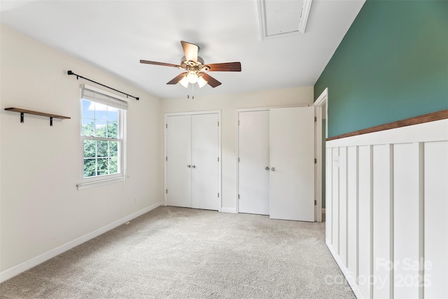 unfurnished bedroom with two closets, baseboards, carpet floors, and ceiling fan