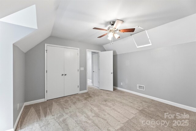 unfurnished bedroom with vaulted ceiling, carpet flooring, ceiling fan, a closet, and baseboards