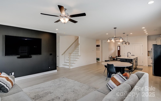 living room featuring recessed lighting, light wood-type flooring, a ceiling fan, and stairs