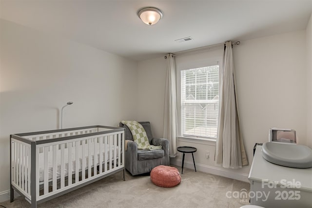 carpeted bedroom featuring baseboards, a nursery area, and visible vents