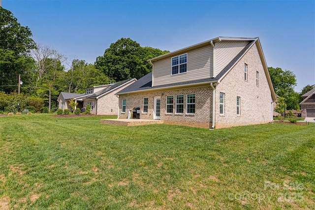 back of house featuring a lawn, a patio, and brick siding