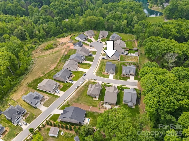 drone / aerial view with a wooded view, a water view, and a residential view