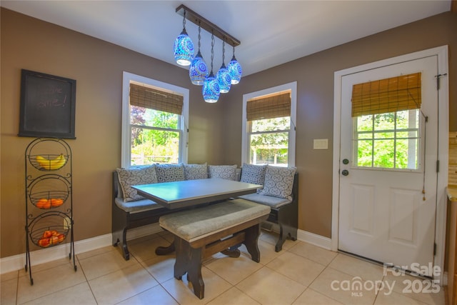 dining space with light tile patterned flooring, baseboards, an inviting chandelier, and breakfast area