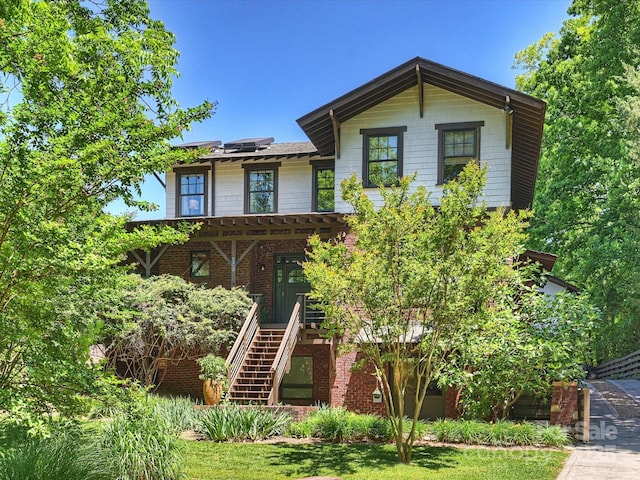 view of front of property with stairway, roof mounted solar panels, brick siding, and a porch