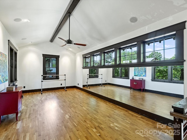 unfurnished living room with healthy amount of natural light, wood finished floors, a ceiling fan, and baseboards
