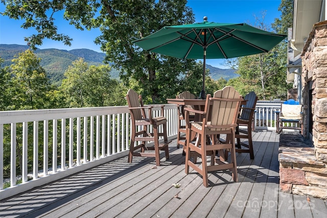 wooden deck with outdoor dining space and a mountain view