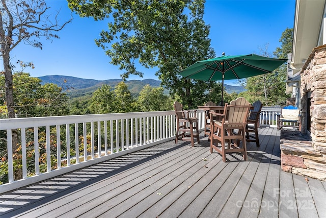 deck with outdoor dining space and a mountain view