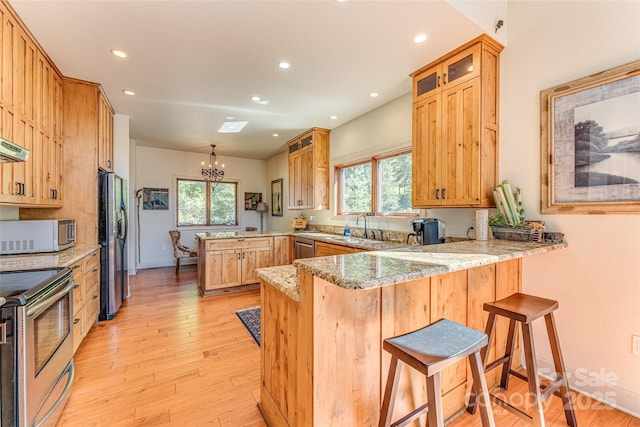 kitchen featuring a healthy amount of sunlight, stainless steel appliances, a peninsula, and an inviting chandelier