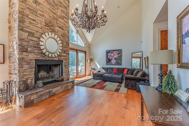 living room featuring light wood-style floors, an inviting chandelier, a fireplace, and a towering ceiling