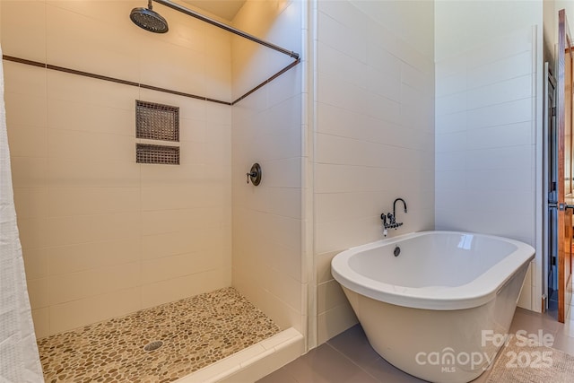bathroom with a freestanding bath, tile patterned flooring, and tiled shower