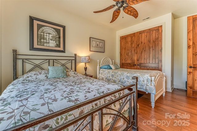 bedroom featuring ceiling fan, baseboards, visible vents, and wood finished floors