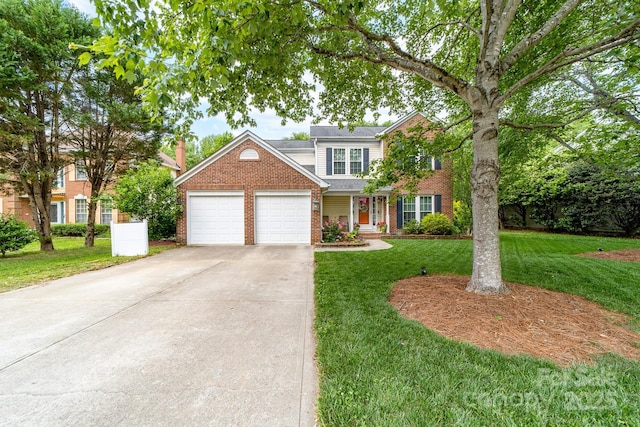 traditional-style house with an attached garage, concrete driveway, a front yard, and brick siding