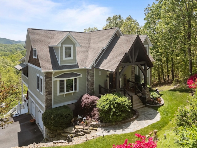 view of front of property with a porch, driveway, roof with shingles, a garage, and stone siding