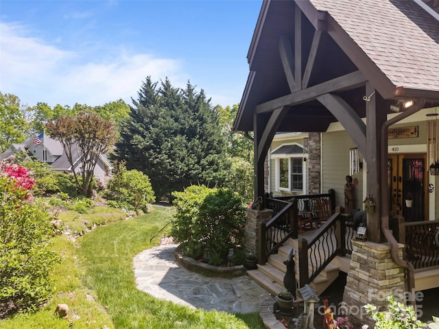 exterior space with roof with shingles and a lawn