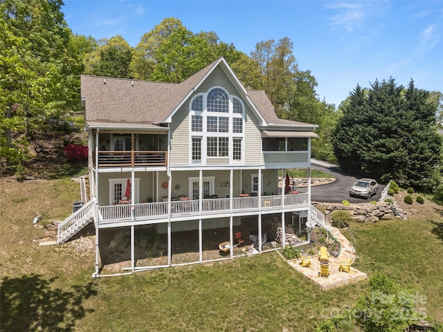 rear view of house featuring stairs, a shingled roof, and a yard