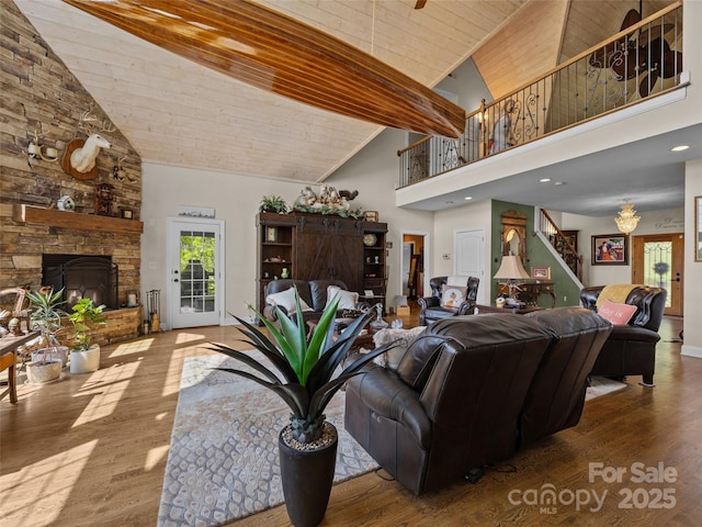 living room with wood finished floors, a stone fireplace, high vaulted ceiling, stairway, and wooden ceiling