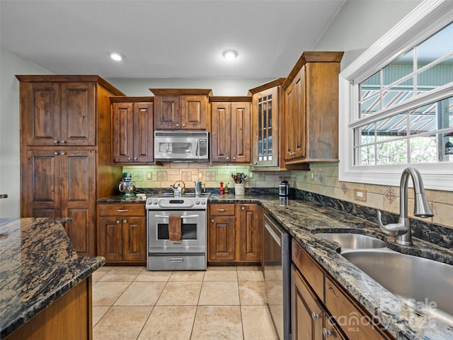 kitchen featuring a sink, dark stone countertops, tasteful backsplash, and stainless steel appliances