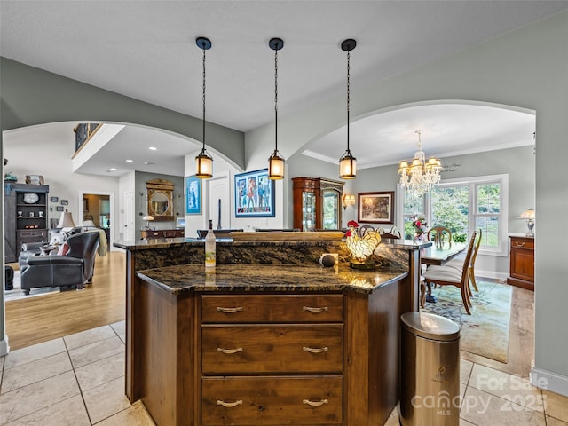 kitchen with crown molding, arched walkways, baseboards, and open floor plan