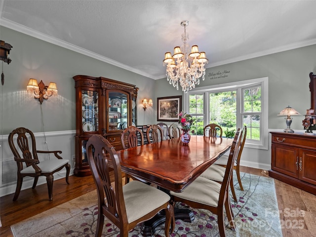 dining room with baseboards, a notable chandelier, ornamental molding, and light wood-type flooring